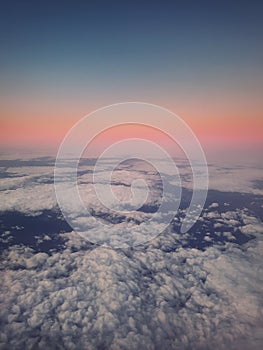 Sunset cloudscape, aerial view out of the plane window above the fluffy clouds. Tranquil sky evening scene, misty nebula. Air
