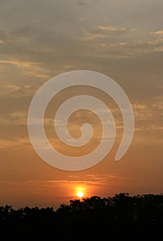 Sunset with cloudy skies over treeline silhouette