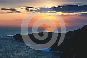 Sunset cloudy sky over the ocean and cliff, Bali.