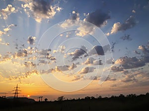 Sunset cloudy sky with picturesque clouds lit by warm sunset sunlight. Country road at sunset