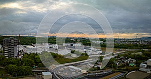 Sunset color in stormy sky over industrial manufacturing plant at edge of town