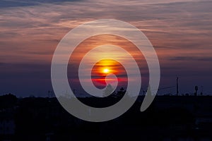 Sunset with colorful clouds and sun on the horizon over the historic city of Palmanova.