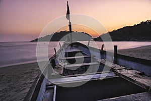 Sunset colorfull pink and violet in a tropical beach goa india with blu boat and island