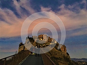 Sunset, colours, pink sky and clouds, tourists and fairytale in Civita di Bagnoregio, town in the province of Viterbo, Italy