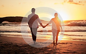 Sunset, couple holding hands and walking by the beach with a beautiful twilight. Love, romance and happy man and woman