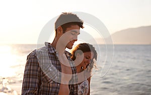 Sunset, couple walking on beach and sea, travel for anniversary or date with bonding, love and support. Calm, peace and