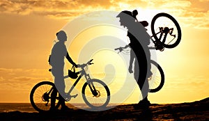 Sunset cyclists. Silhouette of a couple with their bicycles on the beach.