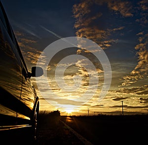 Sunset in the distant with a parked car on the left