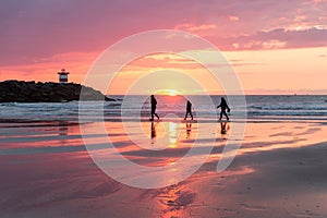 Sunset at the Dutch coast near Scheveningen with passing walkers