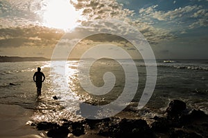 Sunset at the edge of the sea. Silhouette of a man looking at the sun