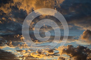 Sunset evening blue sky with fluffy airy yellow orange clouds in sun