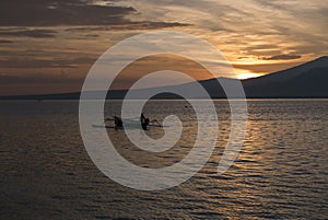 Sunset with fisher man fishing in a boat in ocean near Gili Air