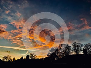 A sunset with flame red skies and trees in silhouette on the landscape