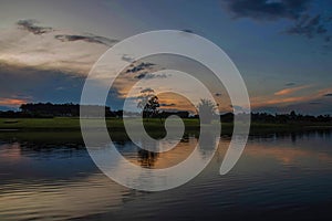 Sunset with forests by the river, with reflection in the water