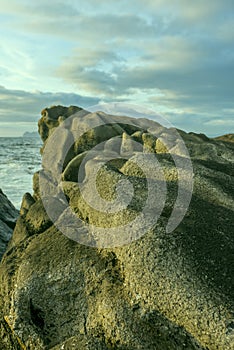 Sunset on the Galician coast of the lower estuaries next to large breakwaters of granodiorite rocks one afternoon with clouds