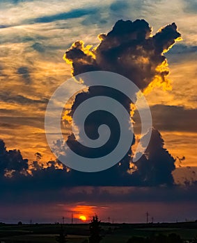 Sunset with glowing sky and a tower of clouds