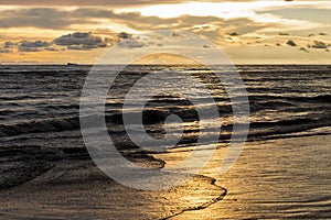 Sunset golden hour in the sea beach with waves and sun reflection