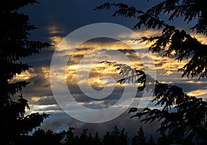 Sunset golden sun rays piercing through dark stormy clouds photo