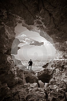 Sunset into grotto and man silhouette.