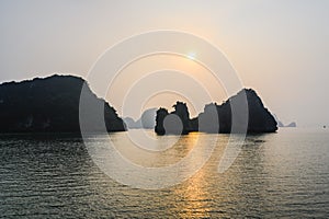 Sunset in Ha Long Bay, Vietnam. Rock formations, misty mood, sunset and reflections in the South China Sea, Vietnam