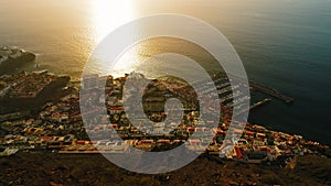 Sunset in harbor town Puerto de Santiago on Tenerife, Canary islands, Spain. Cityscape from above. Sunny golden light is