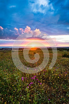 Sunset on the horizon with sky over a rural field and the sea in the background. Sunset, Sunrise over rural meadow field.