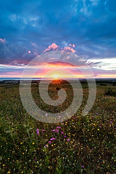 Sunset on the horizon with sky over a rural field and the sea in the background. Sunset, Sunrise over rural meadow field.