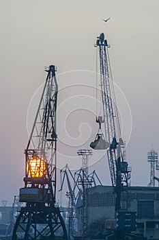 SUNSET WITH INDUSTRIAL SHIPYARD CRANES VERTICAL SHOT