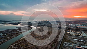 a sunset at an industrial zone with an open river, near a marina