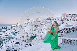 Sunset at the Island Of Santorini Greece, beautiful whitewashed village Oia with church and windmill during sunset Woman