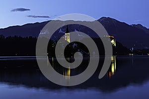 Evening sunset at Lake Bled in Slovenia. Enlightened church on the island, castle ba rock and mountains in the setting sun.