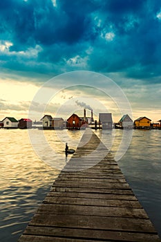 Sunset lake Bokod with pier and fishing wooden cottages