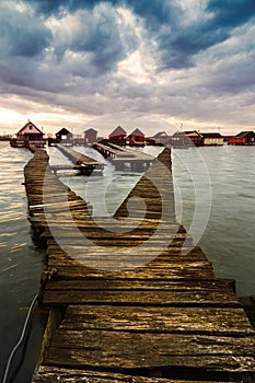 Sunset lake Bokod with pier and fishing wooden cottages