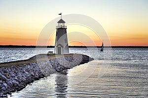 Sunset on Lake Hefner in Oklahoma City, lighthouse in the foreground and a lone sail boat on the water photo