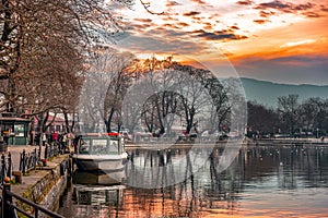 Sunset on lake Pamvotis. Docked boat ready to transfer people to the small island. Greece.