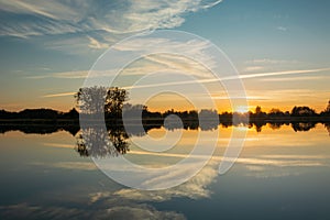 Sunset on the lake and reflection of clouds in the water