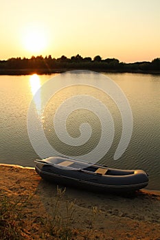 Sunset on the lake with a rubber boat on the shore.