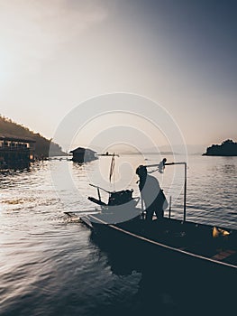 Sunset lake and silhouette of man and motor boat.