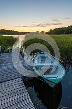 Sunset at the lake and small white boat tied to a dock