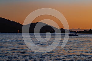 Sunset, lake sparkling. Fishermen driving a small fishing boat in fishing.