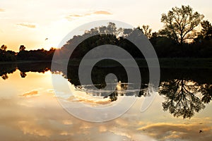 Sunset on the lake. Trees reflected in the water. Evening on th