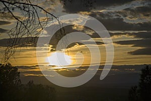 Sunset and lamp with a sky with clouds, gathering some branches of the trees in the parks of Madrid