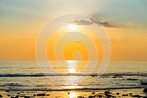 Sunset landscape with beach, sun and stones at sea shore