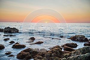 Sunset landscape with golden sun and stones at sea