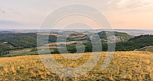 Sunset landscape panorama, hills in golden hour, small village in valley, beautiful colors and clouds.