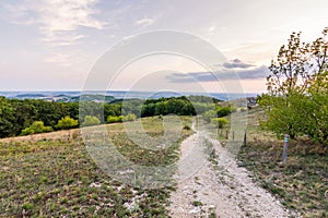 Sunset landscape panorama, hills in golden hour, small village in valley, beautiful colors and clouds.