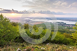 Sunset landscape panorama, hills in golden hour, small village in valley, beautiful colors and clouds.