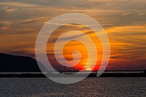 Sunset at lefkas lagoon in greece with dike, water, streetlamps