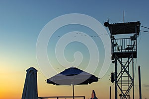 Sunset with life guard station silhouette. Summer background