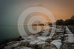 Sunset light behind Chicago skyline with snow covered rocks acting as leading line